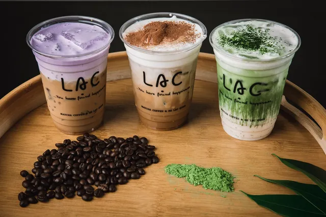 Three Lạc Coffee drinks — ube latte, Vietnamese coffee with cinnamon cream, and matcha — on a wooden tray
